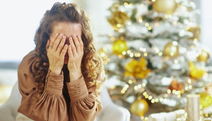 Woman covering her face, feeling overwhelmed by holiday stress
