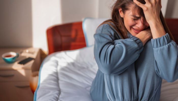Woman sitting on a bed feeling anxious